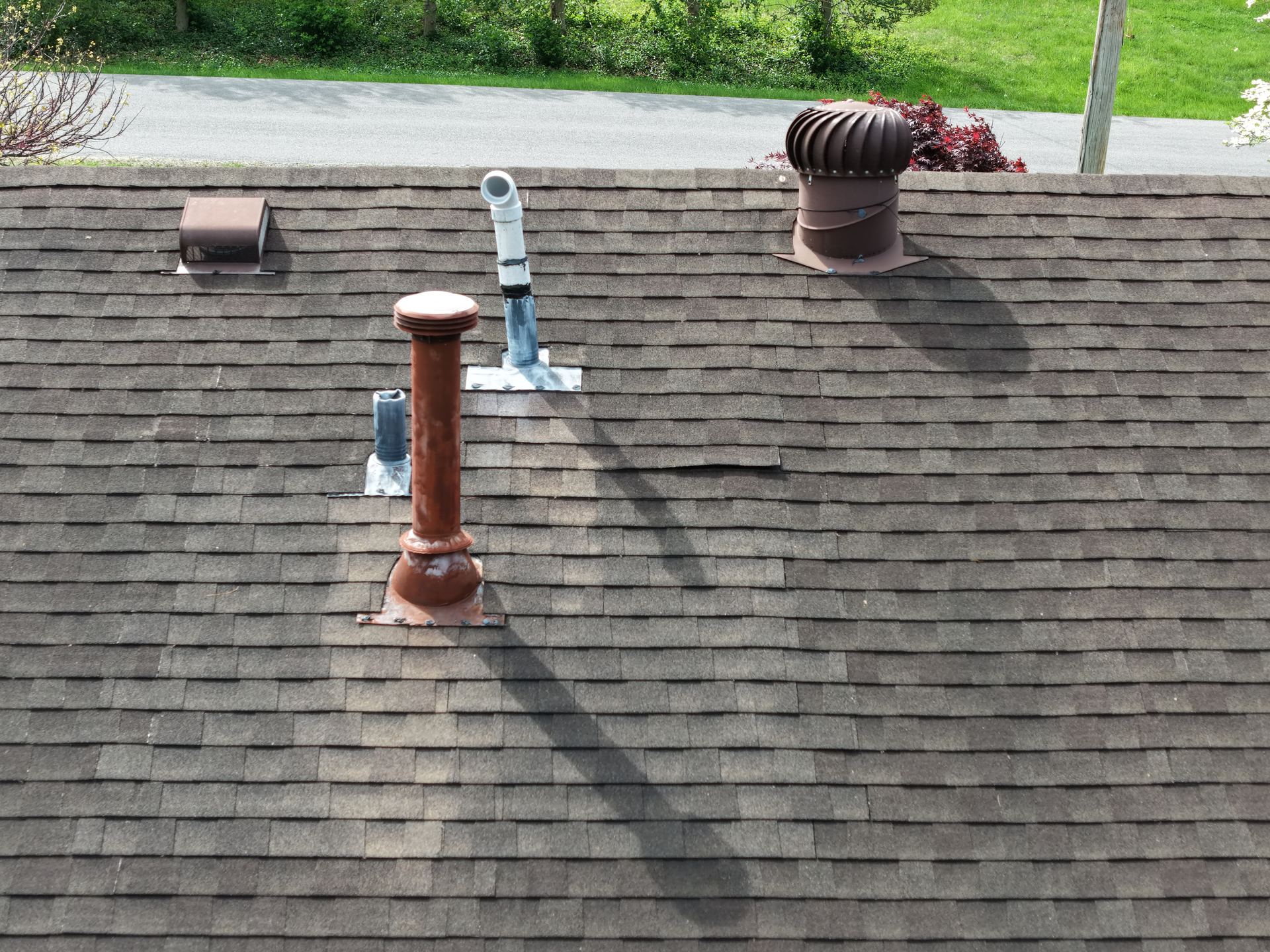Aerial close-up of asphalt shingle roof vents and a lifted shingle identified during a roof inspection