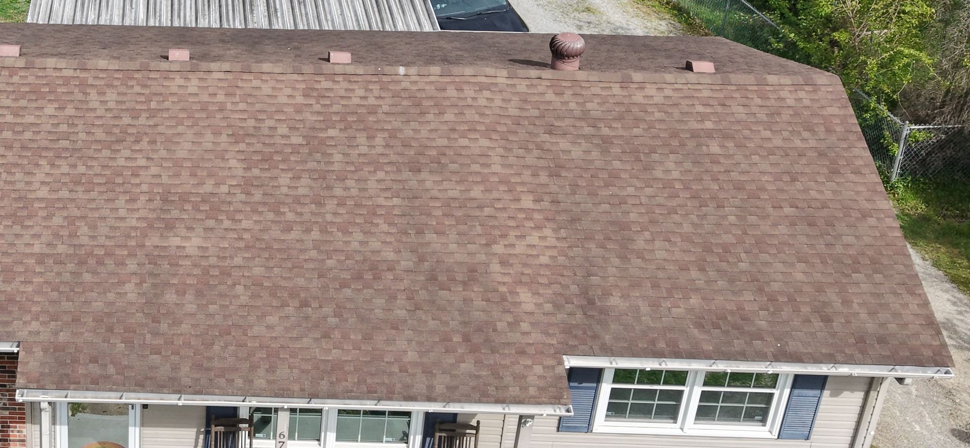 Aerial photo of an asphalt shingle roof edge with vents and gutters near the home's dormer windows